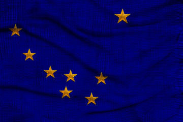 Photo of the national flag of Shatat Alaska USA on a luxurious texture of satin, silk with waves, folds and highlights, closeup, copy space