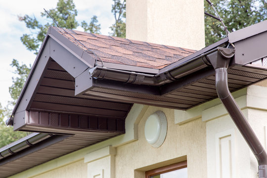 brown roof visor drain gutter on a light building with a white lampshade.