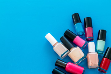 Choose nail polish. Polish bottels on blue background top view copy space