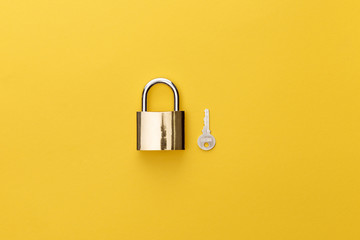top view of padlock near key on yellow background