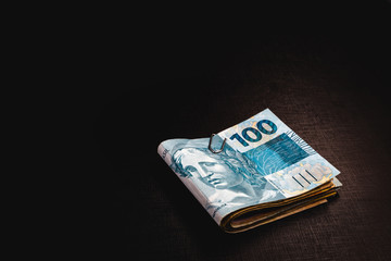 Brazilian money pack on isolated black background. Money from Brazil, called REAL, together on a black table. Concept of financial value or withdrawal from FGTS, banking.