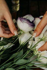 white flowers in a female hand on a wooden table