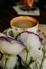 cup of coffee, notebook and white flowers on a wooden table