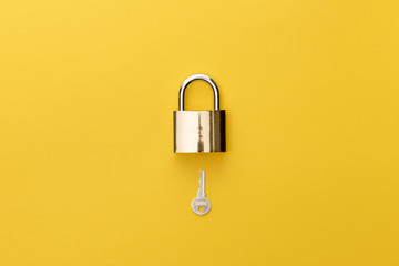 top view of padlock and key on yellow background - Powered by Adobe