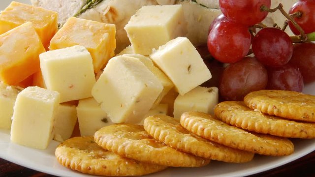 Closeup of a snack plate with cheese, crackers and wrap sandwiches