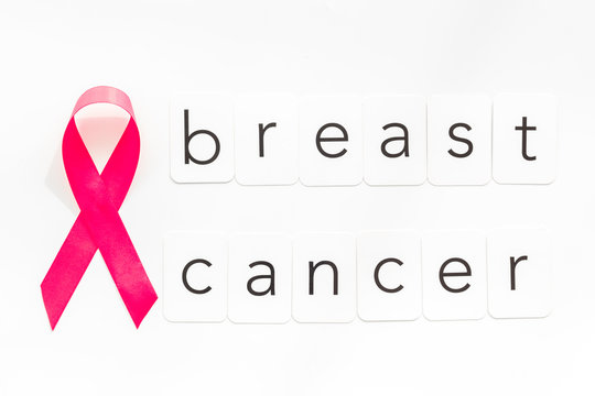Pink ribbon as symbol of breast cancer awareness on white background top view