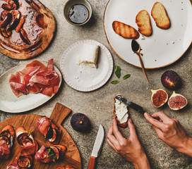 Party or catering food cooking. Flat-lay of crostini with prosciutto, grilled figs and female hands...