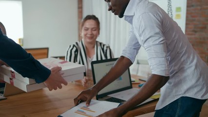Food Delivery Service: Worker Man Courier Brings Pizza in Boxes to the Startup Loft Office for Lunch Break of Diverse Working Team. 4K Corporate Gimbal Follow Shot