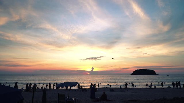 beautiful sunset behind Pu island at Kata beach Phuket. a lot of tourists relax on the beach during sunset..