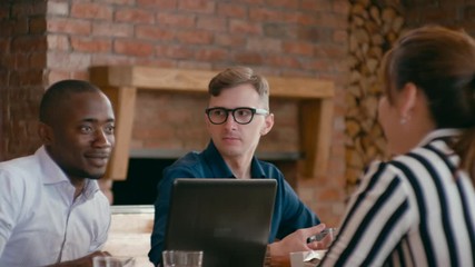 Business Team Enjoy Eating Lunch Together at Workplace with Laptops. Diverse Group of Four People Eats Pizza and Discusses Project in Loft Office. 4K Gimbal Circling Medium Shot