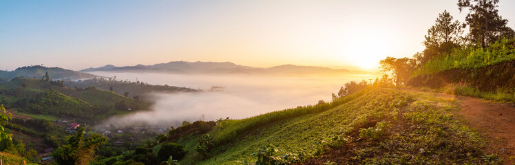 Panoramic mountain trail and village covered in foggy during morning sunrise.