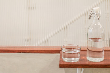 The bottle and clean glass of water on wooden background.selective focus, blur some part.