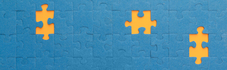 panoramic shot of blue jigsaw puzzle with yellow gaps