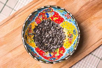 Roasted seeds in beautiful plate on wooden board.