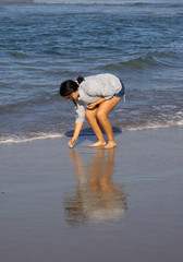 teenager piking up sea shells at Huntintong Beach CA
