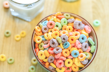 Bowl of colorful children's cereal and milk isolated on wood table with Text space