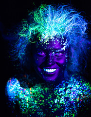 Body art and contact lenses glowing in ultraviolet light. Woman smiling, painted in fluorescent powder. Stars in the eyes