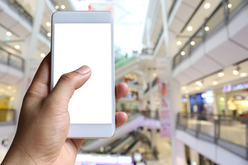 Fototapeta na wymiar Hand of a man holding smartphone device in the Shopping mall background.