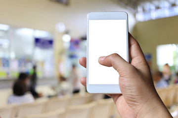 Hand of a man holding smartphone device on blur hospital background.