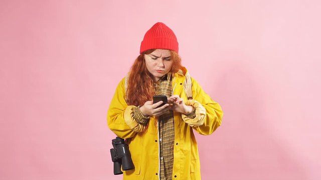 Portrait of a red-haired tourist girl using a mobile phone to view a map