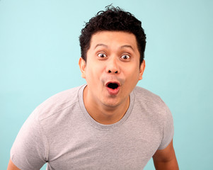 The man in the gray shirt is excited on the blue background..
