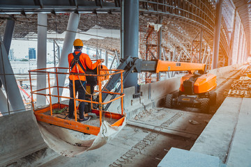  A Engineer wearing safety uniform and safety helmet ,controlling straight Boom Lift to...