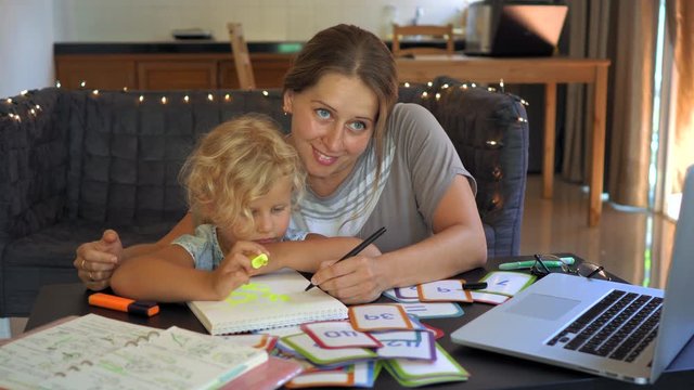 A teacher, a tutor for home schooling. a teacher or mom at the table with a little girl. Homeschooling concept