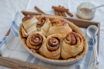 Cinnamon rolls with sugar frosting. With cinnamon sticks and spices, wooden background 