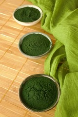 Obraz na płótnie Canvas Spirulina seaweed. Spirulina powder in ceramic cups set on bamboo mat background.Healthy food.