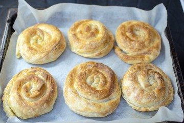 Handmade pieces of cheese pie baked with parchment paper in a pan.