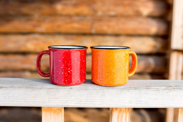 Two coffee mugs on the porch of a wooden house. Autumn and winter season.