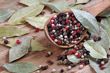 dry bay leaf on a wooden table. bay leaf and pepper mixture in a wooden spoon © Oleksii