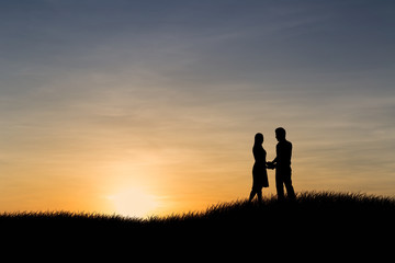 Fototapeta na wymiar Silhouettes of couple man and woman in nature sunset background. Love concept.