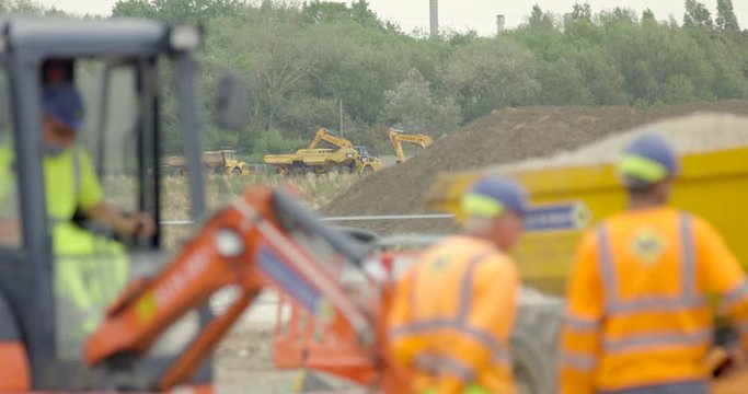 Large Industrial Crane Vehicle and Workmen on Construction Site. Digger Moving Quarry Earth in Britain.