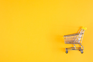 Shopaholic. Buyer. Shopping concept. Close-up. Isolated shopping trolley on a yellow background....