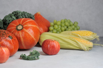 Pumpkins, corn on the cob, cale salad, grapes, apples. Autumn harvest concept - fruits and...