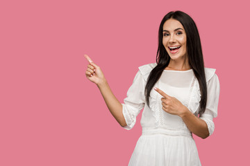 cheerful woman smiling while pointing with fingers isolated on pink