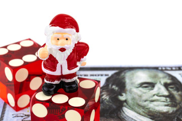 Santa Claus toy stands on a dice lying on a banknote with a portrait of Benjamin Franklin and wishes you a Merry Christmas / good luck concept in 2020. Isolated on white.