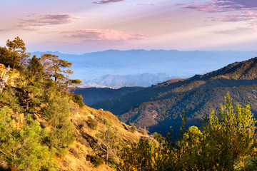 Sunset view of hills and valleys in the Santa Cruz mountains; South Clara Valley and Diablo mountain range visible in the background