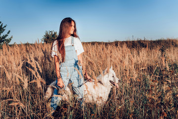 Girl in the field with her dog. The gaze of both is directed into the distance. Dog breed Samoyed...