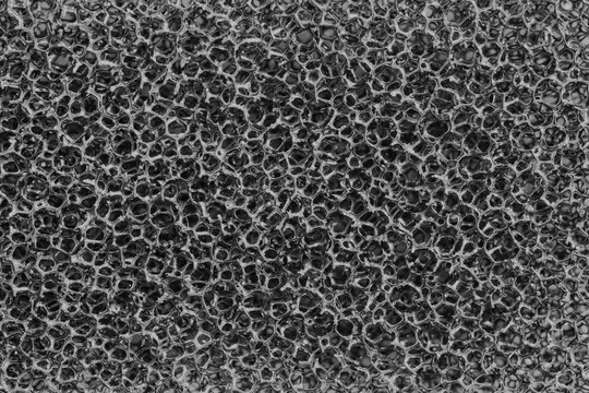 The surface texture of a black sponge for washing and wet cleaning of plastic strands, abstract background