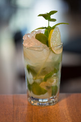 Refreshing mint cocktail mojito with rum and lime, cold drink or beverage with ice on white wooden background, top view