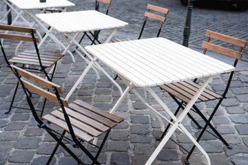 wooden chairs with summer table standing on the street on them the sun rays, tables near cafe