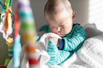 Cute baby sitting on a chair in front of colorful rainbow toys