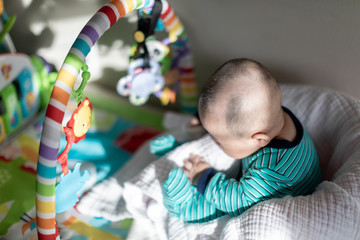 Cute baby sitting on a chair in front of colorful rainbow toys