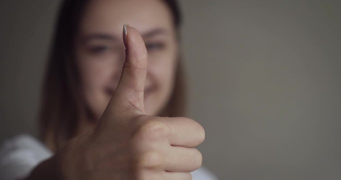 Young woman shows thumbs up sign.