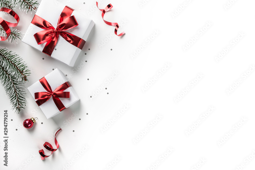 Wall mural christmas fir branches with gift boxes with red ribbon on white paper background with bokeh, light. 