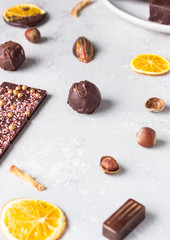 Assortment of sweet confectionery with chocolate candies and pralines on a light grey stone background. 