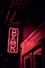 neon BAR sign lights up the doorway of a drinking establishment