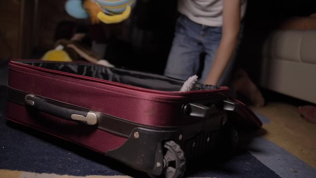 boy puts toys in a suitcase, getting ready for the road, travel concept